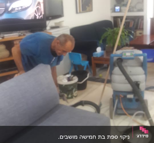 אדם מנקה ספה עם מכונת ניקוי מקצועית